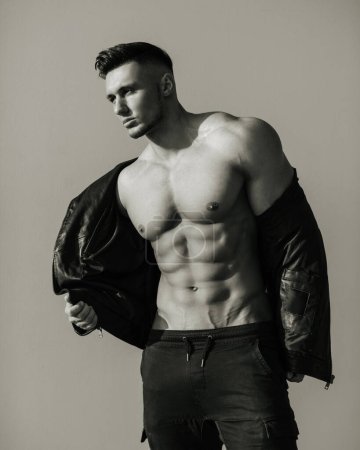 Black and white portrait of handsome man in leather jacket. Sexy male model in brutal look. Biker style shot of muscular guy.