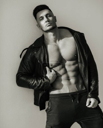 Black and white portrait of handsome man in leather jacket. Sexy male model in brutal look. Biker style shot of muscular guy.