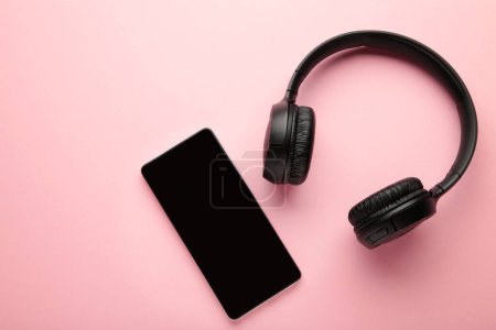 Photo for Black smartphone and wireless headphones on a pink background. Top view. - Royalty Free Image