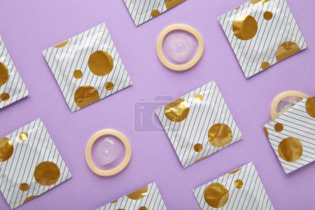 Geöffnetes Kondom und Kondom in Packung auf lila Hintergrund. Kondomgebrauch zur Verringerung der Wahrscheinlichkeit einer Schwangerschaft oder sexuell übertragbarer Krankheiten. Ansicht von oben