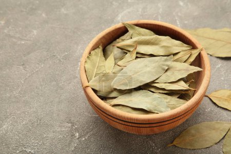 Bay leaves in wooden bawl on a concrete background. Top view