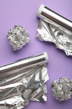 Rolls of aluminum foil on purple background. Vertical photo. Top view