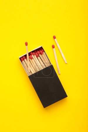 Box of matches on yellow background. Vertical photo. Top view