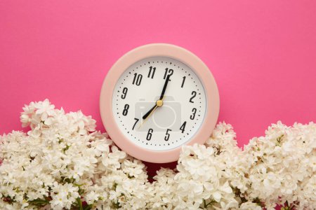 Foto de Reloj con flores blancas sobre fondo rosa. Vista superior - Imagen libre de derechos