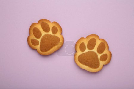 Self made cat paw cookies on purple background. Top view