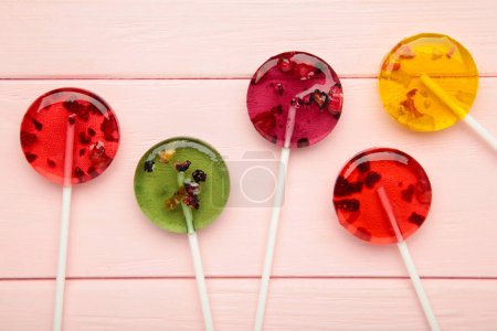 Foto de Coloridas piruletas dulces con bayas sobre fondo rosa. Vista superior - Imagen libre de derechos