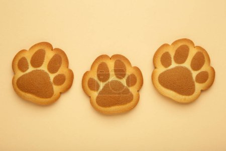 Self made cat paw cookies on beige background. Top view