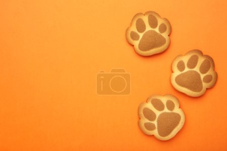 Self made cat paw cookies on orange background. Top view
