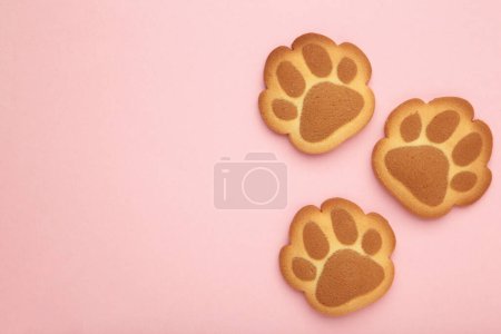 Self made cat paw cookies on pink background. Top view