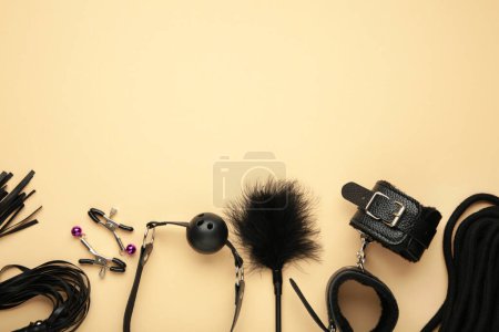 Photo for Set of erotic toys for BDSM on beige background. The game of sexual slavery with a whip, gag and leather blindfold. Intimate sex games. Top view - Royalty Free Image