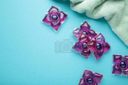 Laundry capsules with mint towel on blue background. Laundry detergent for washing clothes in a washing machine. Top view
