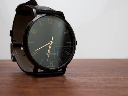 Foto de Water resistant black watch with leather strap placed on a wooden desk - Imagen libre de derechos