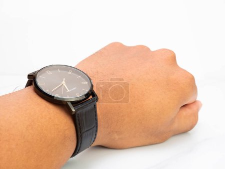 Foto de Water resistant black watch with leather strap wear by asian man on left hand, isolated with white background - Imagen libre de derechos