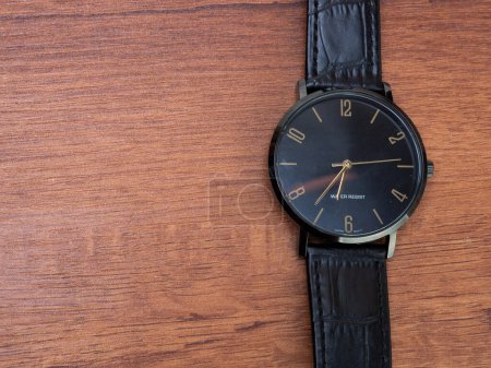 Foto de Water resistant black watch with leather strap shoot with top view style on a wooden table - Imagen libre de derechos