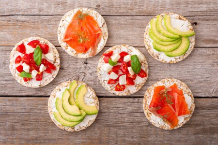 Photo for Protein toast ceispbread with delicious toppings top view : avocado, salmon, vegetables, tomatoes, herbs and cheese - Royalty Free Image