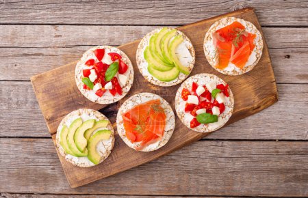 Photo for Protein toast ceispbread with delicious toppings top view : avocado, salmon, vegetables, tomatoes, herbs and cheese - Royalty Free Image