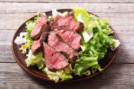 Salat mit gegrilltem Rindfleisch mittlerer Braten. Auf Holzgrund