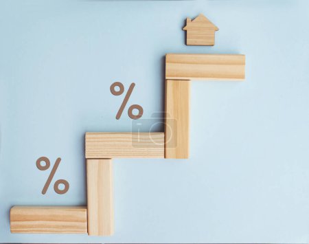 Housing market and property value concept with small wooden house and percent signs . Mortgage rates
