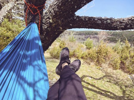 Women's legs in a hammock in a summer park