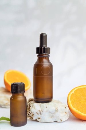 Foto de Botella de vidrio ámbar con vitamina C. Suero de vitamina C con fruta naranja - Imagen libre de derechos