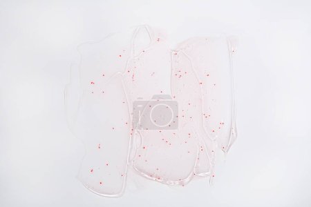 Photo for Top view of facial transparent gel with red exfoliating particles on light surface - Royalty Free Image