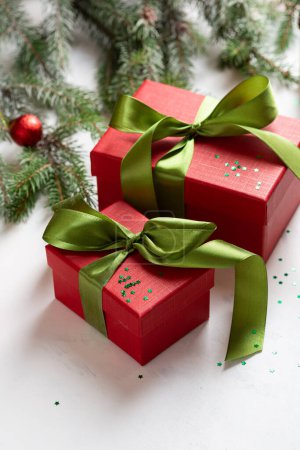 Téléchargez les photos : Gros plan de boîte cadeau de Noël rouge avec arc vert concept de vacances nature morte - en image libre de droit