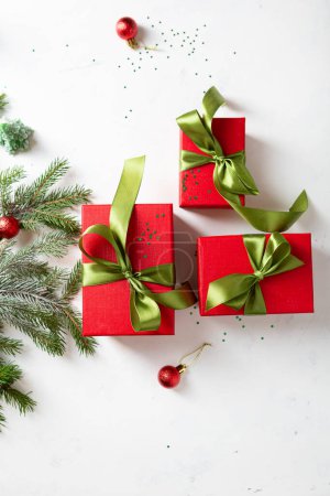 Photo for Red Christmas present box with green bow and fir branches top view - Royalty Free Image