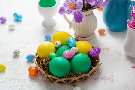 Osterfeststillleben mit grünen und gelben Eiern und Blumen