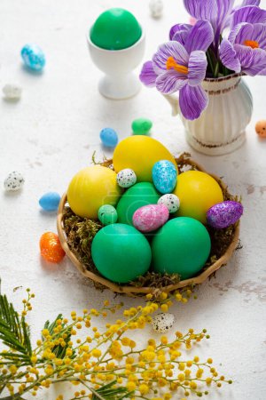 Téléchargez les photos : Easter holiday still life with green and yellow eggs and flowers on light surface - en image libre de droit