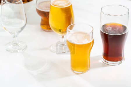 Foto de Set de vidrio con cerveza clara oscura sobre fondo claro concepto de fiesta - Imagen libre de derechos