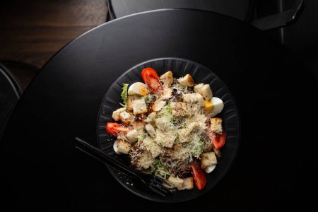 Téléchargez les photos : Salade César sur assiette sur table noire vue de dessus - en image libre de droit