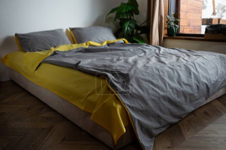 Téléchargez les photos : Oreiller de literie en coton jaune et gris et couverture sur le lit plante d'intérieur - en image libre de droit