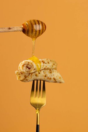 Foto de Miel vertiendo crepes franceses panqueque en la comida tenedor - Imagen libre de derechos