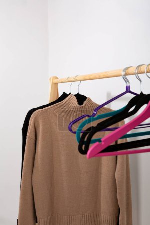 Photo for Beige and black wool sweater hanging on a wooden hanger cozy clothing - Royalty Free Image