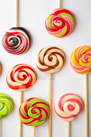 Téléchargez les photos : Sucette sucrée pop bonbons tourbillonnants sur fond alimentaire de surface blanche - en image libre de droit