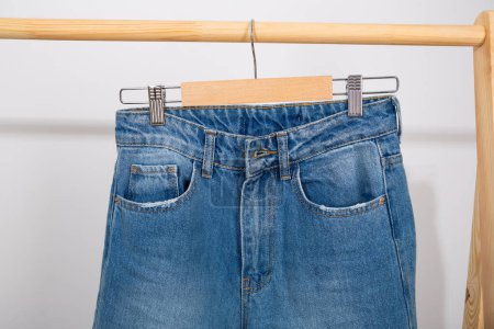 Photo for Blue denim pants on a hanger conscious consumption - Royalty Free Image