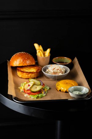 Foto de Los ingredientes de la hamburguesa con el queso a la mesa negra las patatas fritas - Imagen libre de derechos