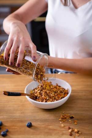 Photo for Granola falling down from jar in bowl cooking food - Royalty Free Image