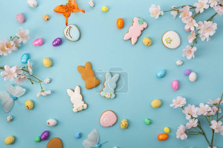 Photo for Easter cocnept colour eggs and bunny cookies on blue surface - Royalty Free Image