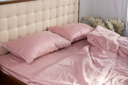 Foto de Ropa de cama de satén rosa pálido y almohadas mañana desordenado - Imagen libre de derechos