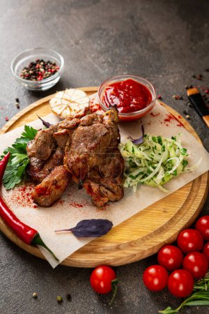 Foto de Trozos de carne a la parrilla en una tabla y verduras frescas - Imagen libre de derechos
