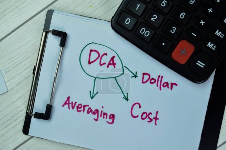 Konzept von DCA - Dollar Cost Averaging schreiben auf Papierkram mit Taschenrechner isoliert auf Holztisch.