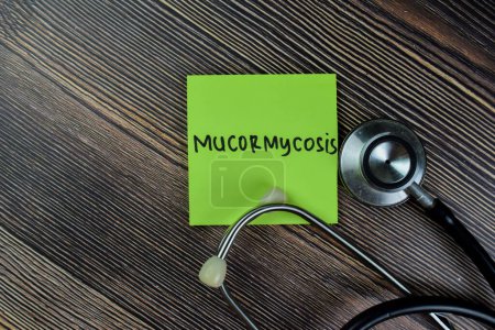 Photo for Concept of Mucormycosis write on sticky notes with stethoscope isolated on Wooden Table. - Royalty Free Image