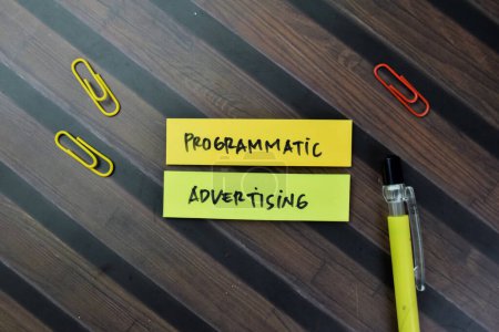 Concept of Programmatic Advertising write on sticky notes isolated on Wooden Table.