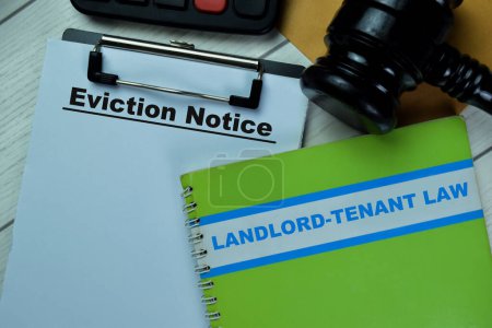 Photo for Concept of Eviction Notice text on Document and book Landlord-Tenant Law isolated on Wooden Table. - Royalty Free Image