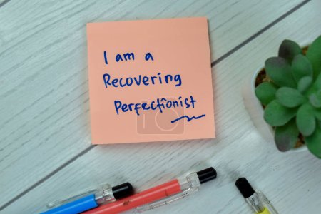 Téléchargez les photos : Concept of I am a Recovering Prefectionist write on sticky notes isolated on Wooden Table. - en image libre de droit