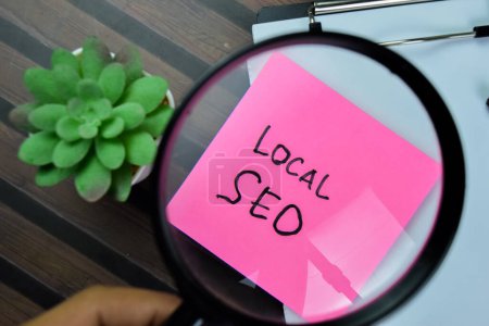Concept of Local SEO write on sticky notes with magnifying glass isolated on Wooden Table.