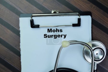 Foto de Concepto de cirugía de Mohs escribir en el papeleo con estetoscopio aislado en la mesa de madera. - Imagen libre de derechos