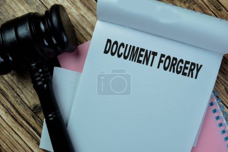 Concept of Document Forgery write on book with gavel isolated on Wooden Table.