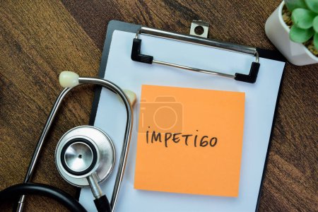 Konzept von Impetigo schreiben auf klebrige Notizen mit Stethoskop isoliert auf Holztisch.